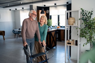 Un aîné marche à l’aide d’un déambulateur dans sa maison, illustrant comment adapter le domicile pour vieillir chez soi.