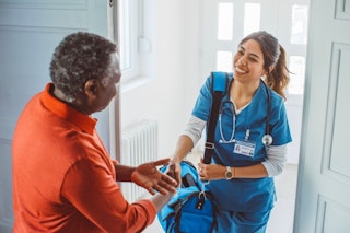 Infirmière du réseau public accueillie par un aîné, illustrant les soins publics à domicile pour aînés.