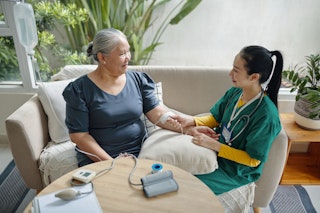 Aînée recevant des soins médicaux à domicile d’une infirmière, illustrant les services de type hôpital à domicile.