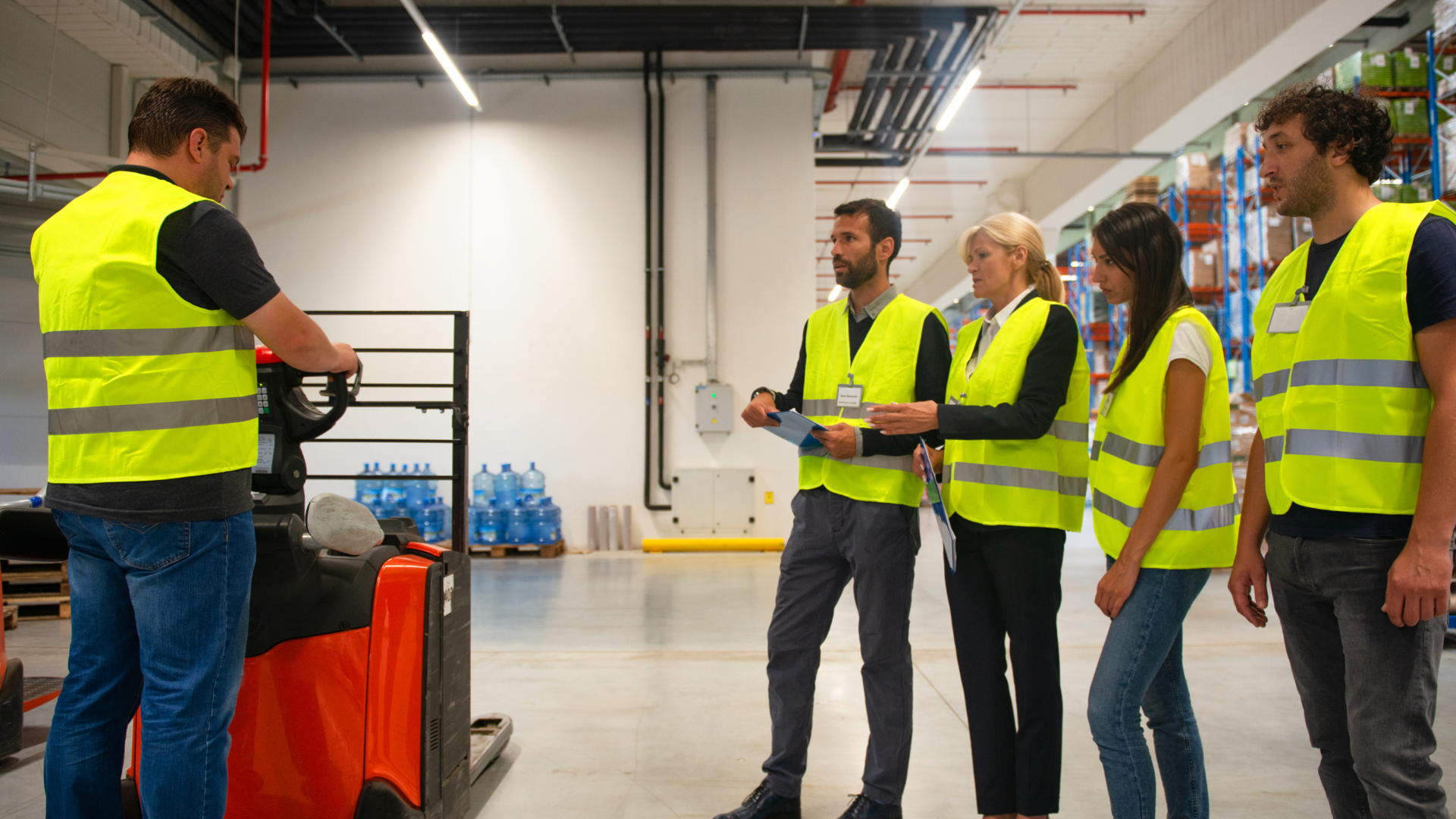 Un formateur expliquant à des travailleurs et des travailleuses l'utilisation sécuritaire d'un transpalette électrique.