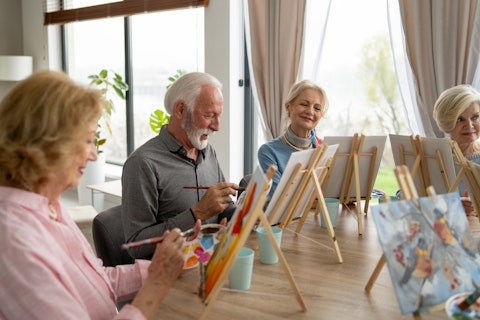 Seniors engage wholeheartedly in a casual painting class, surrounded by fellow learners, enjoying the process of creating beautiful artworks together.