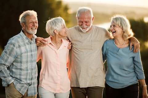 Group of cheerful mature people having fun while talking and walking embraced outdoors.