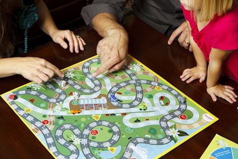 Young family playing a board game with their daughter. NOTE: I had the creator and copyright holder for the game itself. It is all my original artwork and completely fictional.